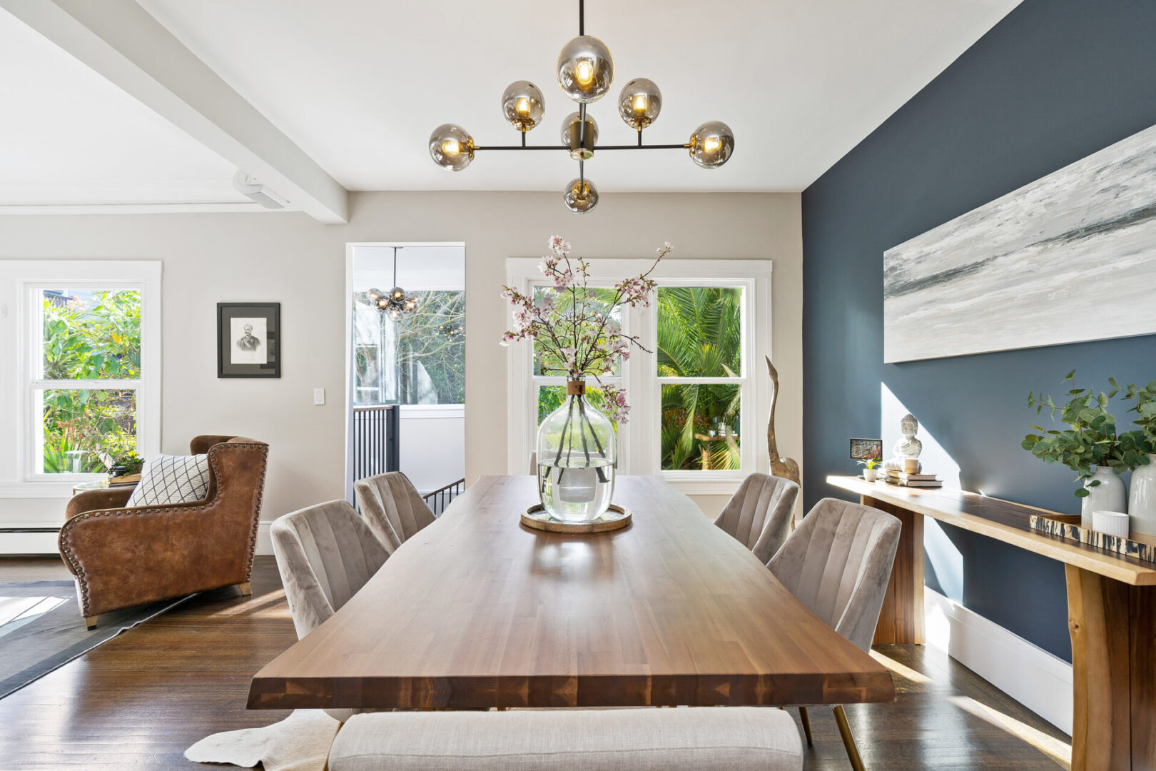 A dining room table with chairs and a vase of flowers.