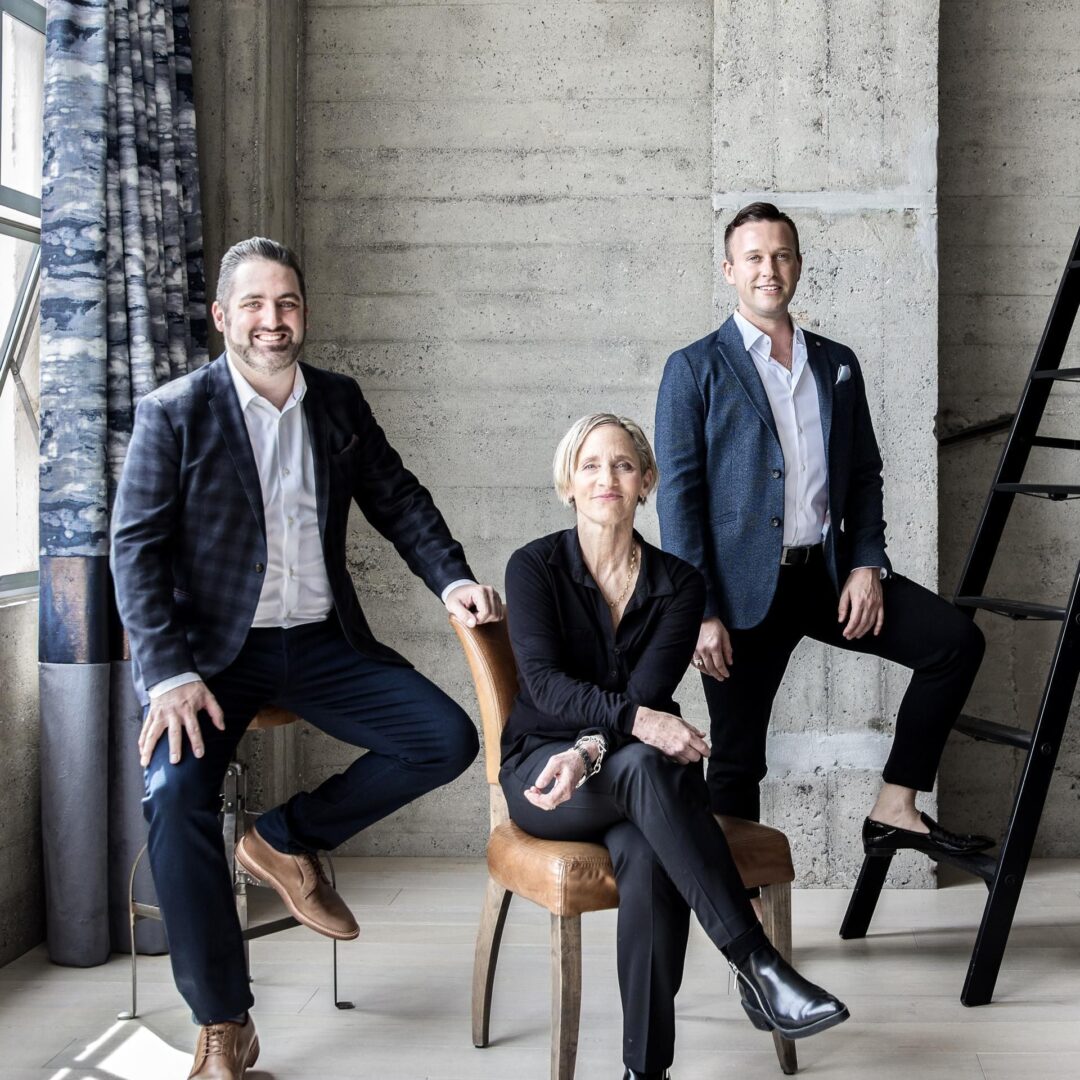 Three people sitting on a chair in front of a wall.